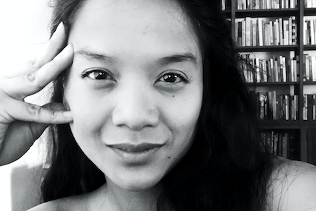 A long hair Asian woman in front of a bookshelf